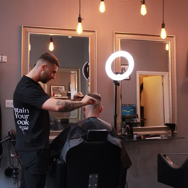 A barber at work at a station lit by a ring light