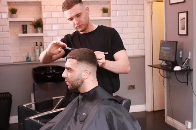 A barber checking a fade with a comb